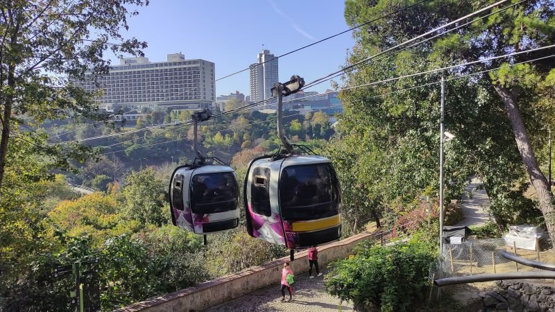 Two cabins of the Maçka cable car above the trees of the park