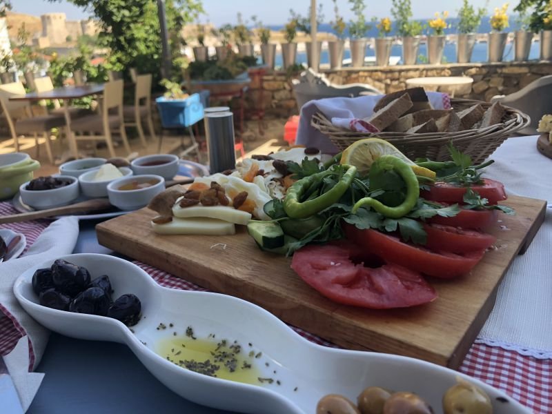 A Turkish breakfast board with tomatoes, green peppers, cheese, olives and bread, served on a terrace